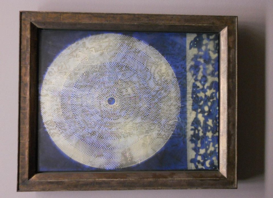 A framed painting by Max Ernst: a pale, finely textured circular form like a galaxy on a deep blue ground.